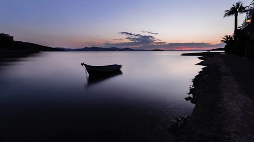 Boat moored on sea against sky during sunset