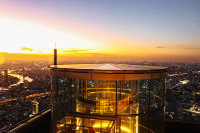 Illuminated cityscape against sky during sunset