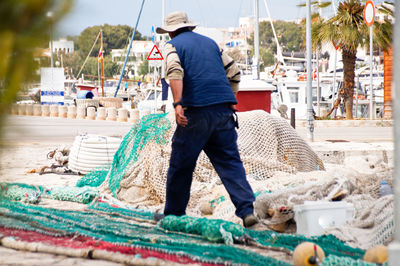 Full length of fisherman walking amidst fishing nets at harbor