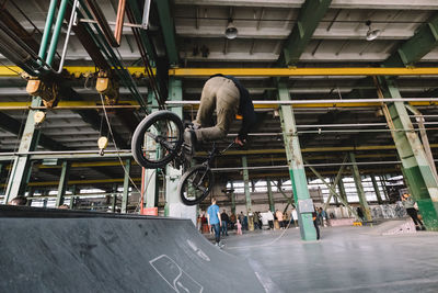 Unrecognizable bmx rider is performing tricks in indoor skatepark. young male doing jump tricks