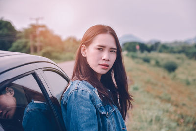 Portrait of beautiful woman sitting on field against sky