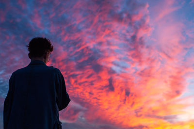 Rear view of silhouette man against sky during sunset