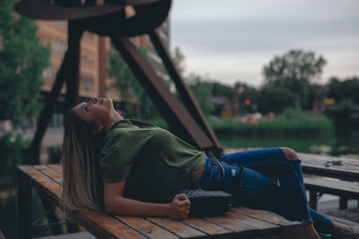 Young woman leaning on bench in park