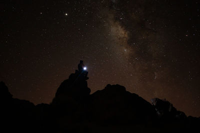 Low angle view of silhouette rock formation against sky at night