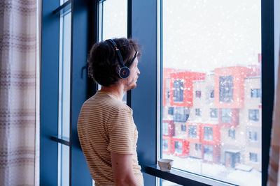 Adult programmer with a cup of tea talks to coworkers using a wireless headset 