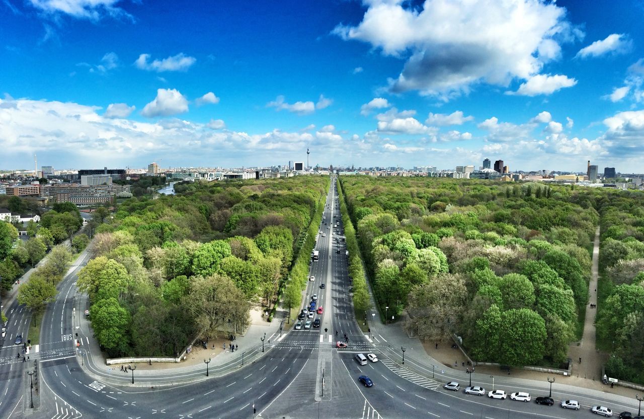 transportation, road, sky, tree, car, cloud - sky, high angle view, the way forward, built structure, land vehicle, architecture, road marking, city, cloud, street, blue, vanishing point, diminishing perspective, mode of transport, day