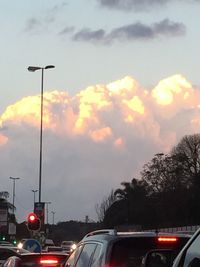Cars on road against cloudy sky