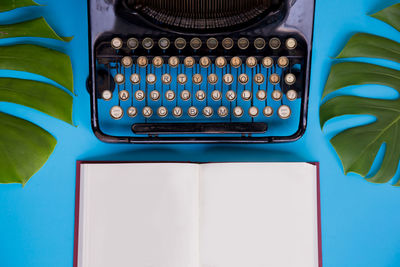 Close-up of typewriter and book against blue background