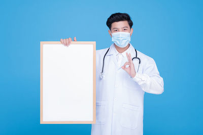 Young man standing against blue background