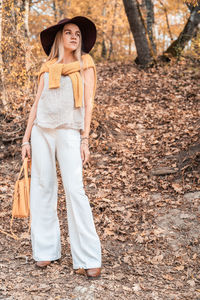 Portrait of beautiful young woman standing against tree