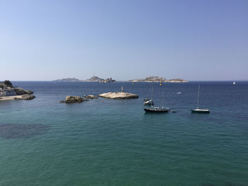 Sailboats in sea against clear blue sky