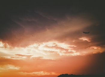 Low angle view of silhouette airplane flying against sky during sunset