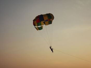 Low angle view of silhouette people parasailing against sky during sunset