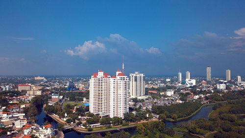 Aerial view of buildings in city against cloudy sky