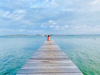 Man on pier over sea against sky