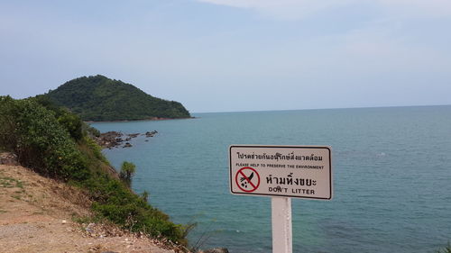 Close-up of information sign by sea against clear sky