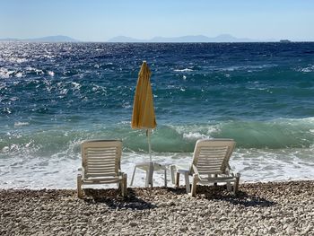 Empty chairs on beach against sea