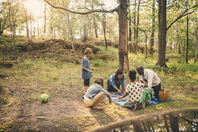 Multi-ethnic family enjoying picnic against trees at public park