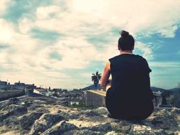 Rear view of a man standing against cloudy sky