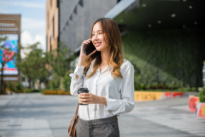 Young woman using mobile phone in city