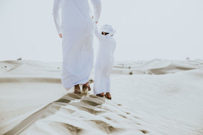 Low section of father with son enjoying while walking in desert