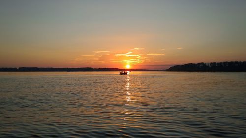 Scenic view of boat on sea at sunset