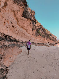 Rear view of woman walking on rock