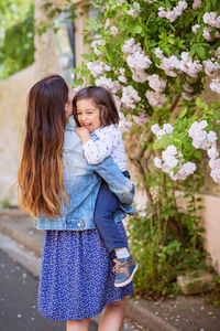 Mother and little handsome baby boy looking at bush with white roses