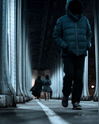 Rear view of people walking on footpath in city