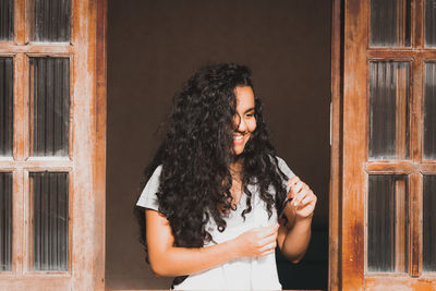 Young woman looking away while standing against door