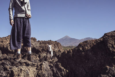 Man standing on rock against sky