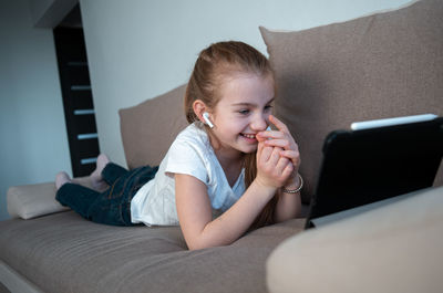 Boy using mobile phone while sitting on sofa at home