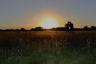 Men on field against sky during sunset