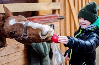 Smiling boy feeding apple to horse