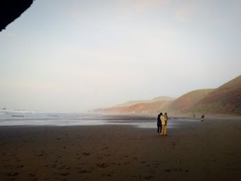 People walking on beach against sky