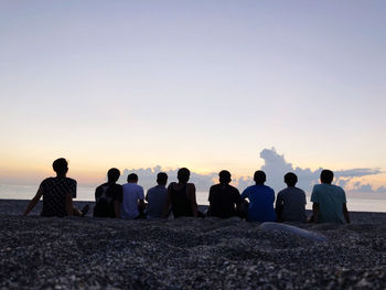 Rear view of people sitting on beach