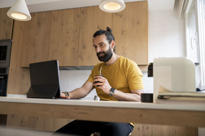 Full length of man using mobile phone while sitting on table