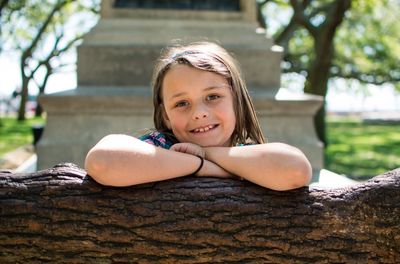 Portrait of girl leaning on fallen tree