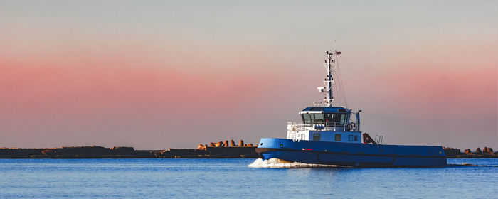 Ship sailing in sea against sky during sunset