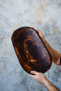 Close-up of hand holding wood against wall