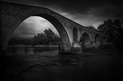 Arch bridge over river against sky