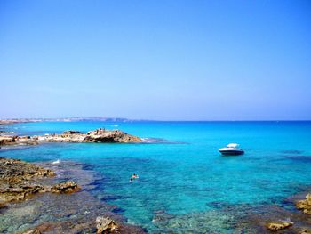 Boat in calm blue sea against clear sky