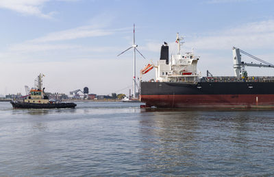 The photo shows a cargo ship pulled by a harbor tugboat