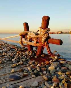 Close-up of mooring bolard on wooden pier against sunset sky