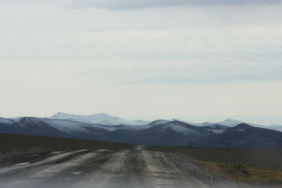 Road leading towards mountains against sky