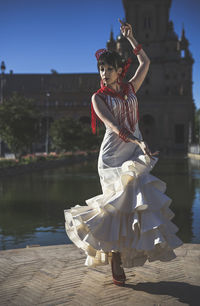 Woman doing flamenco dance by lake in city 