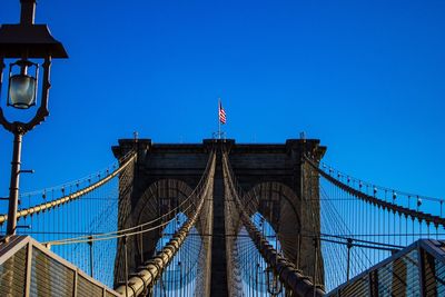 Low angle view of suspension bridge against blue sky