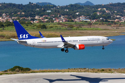 Airplane flying over airport runway against sky