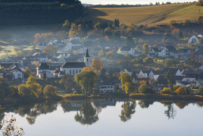 Scenic view of lake by houses against sky