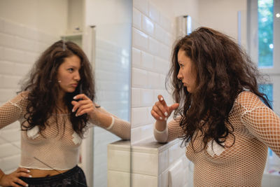 Angry woman gesturing while looking at her reflection in mirror at home